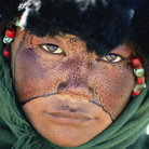Una ragazza nomade con il volto cosparso di una sostanza protettiva durante un pellegrinaggio Tibet, Cina 1990. © Kazuyoshi Nomachi