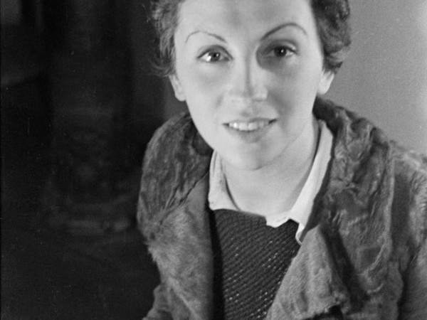 Portrait of Gerda Taro as she looks up from a typewriter on a desk, Paris, 1936