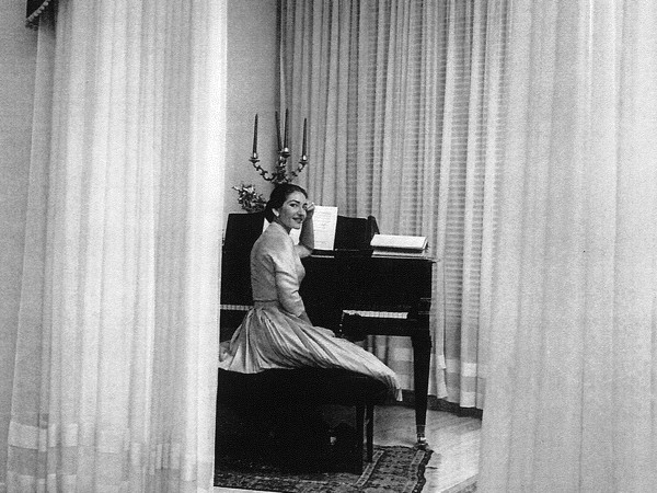 Maria Callas nella sua casa milanese seduta al pianoforte, con il candelabro donatole dal Teatro alla Scala, 1955 | Courtesy of Arthemisia Group e Gruppo AGSM
