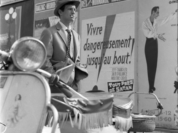 Foto fuori dal set. Belmondo di fronte ad un cartellone: “Vivere pericolosamente, fino alla fine!” 