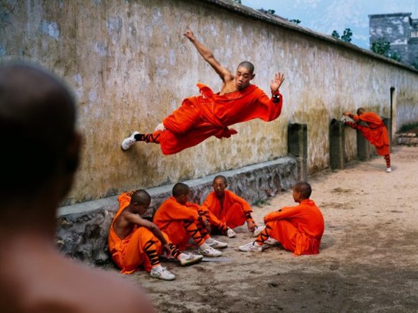 Steve McCurry, A young monk runs along the wall over his peers, Hunan, China, 2004