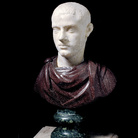 Scultore romano del 220-235 d. C. circa (ritratto), del II-III secolo d.C. (busto), il piedistallo è moderno, Busto in porfido con ritratto virile, marmo bianco pentelico (testa) inserita in busto in porfido con piedistallo modanato in serpentino, altezza 26 cm. Roma, Fondazione Dino ed Ernesta Santarelli