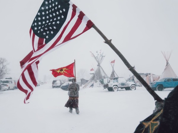 Contemporary Issues - First Prize, Stories © Amber Bracken, Standing Rock, Alcune persone portano la bandiera americana e quella della Mohawk Warrior Society al campo di protesta contro il Dakota Access Pipeline, in Cannon Ball, North Dakota, USA